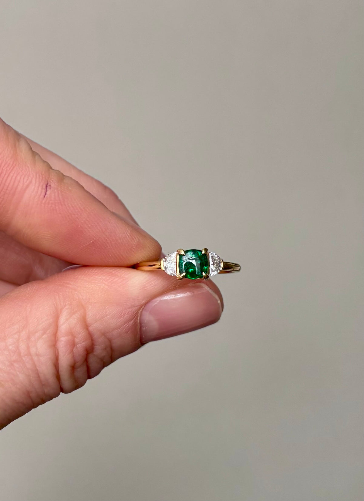 Cushion cut emerald on yellow gold band. Yellow gold trilogy.