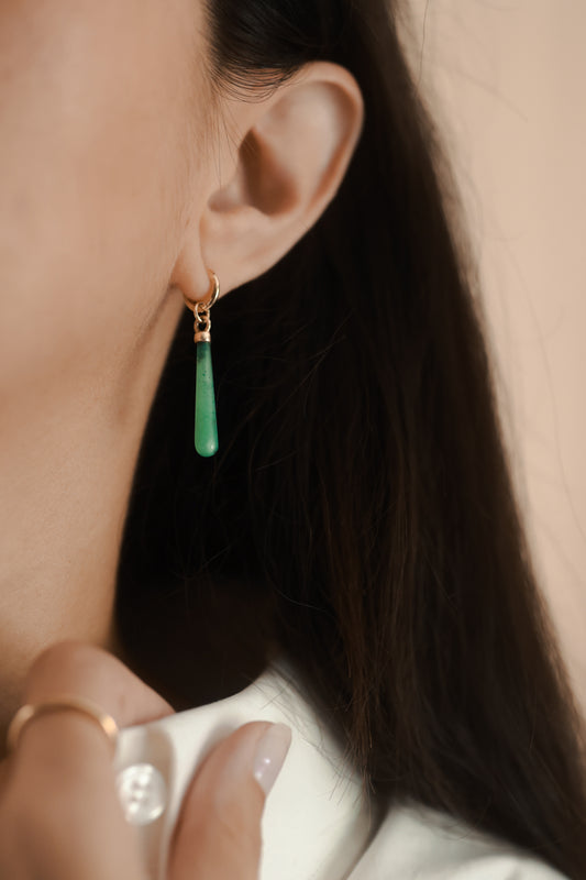 Green teardrop earrings on a model.