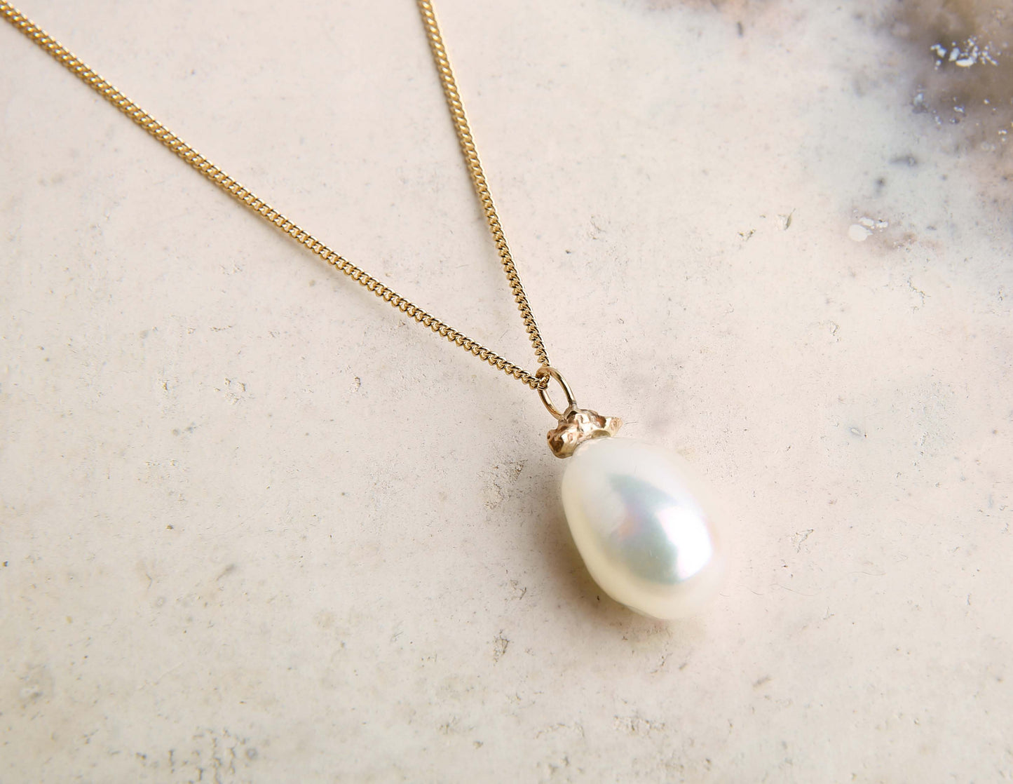 Baroque pearl and gold nugget pendant necklace on pink marbled background