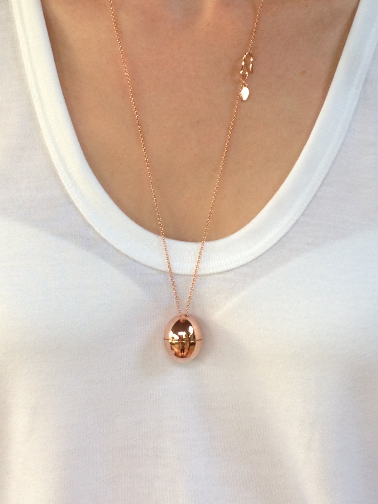 rose gold egg shaped locket on white tshirt