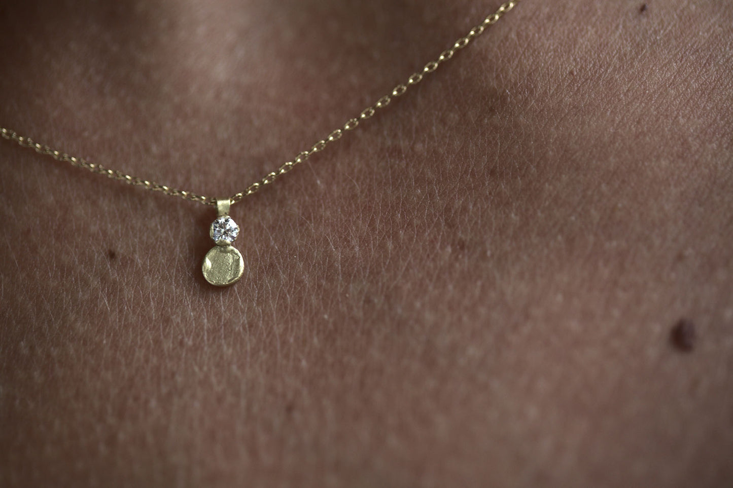 handmade 18ct gold disc pendant necklace with diamond on model's neck