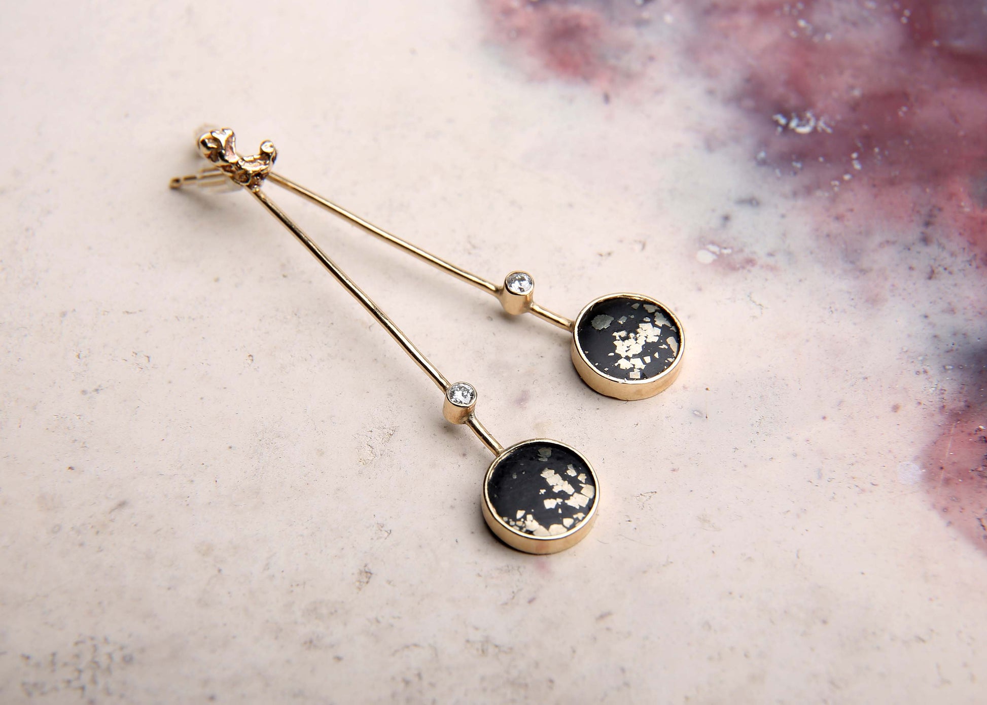 Stem black and gold drop earrings with diamond and gemstone slate pyrite on pink marbled background