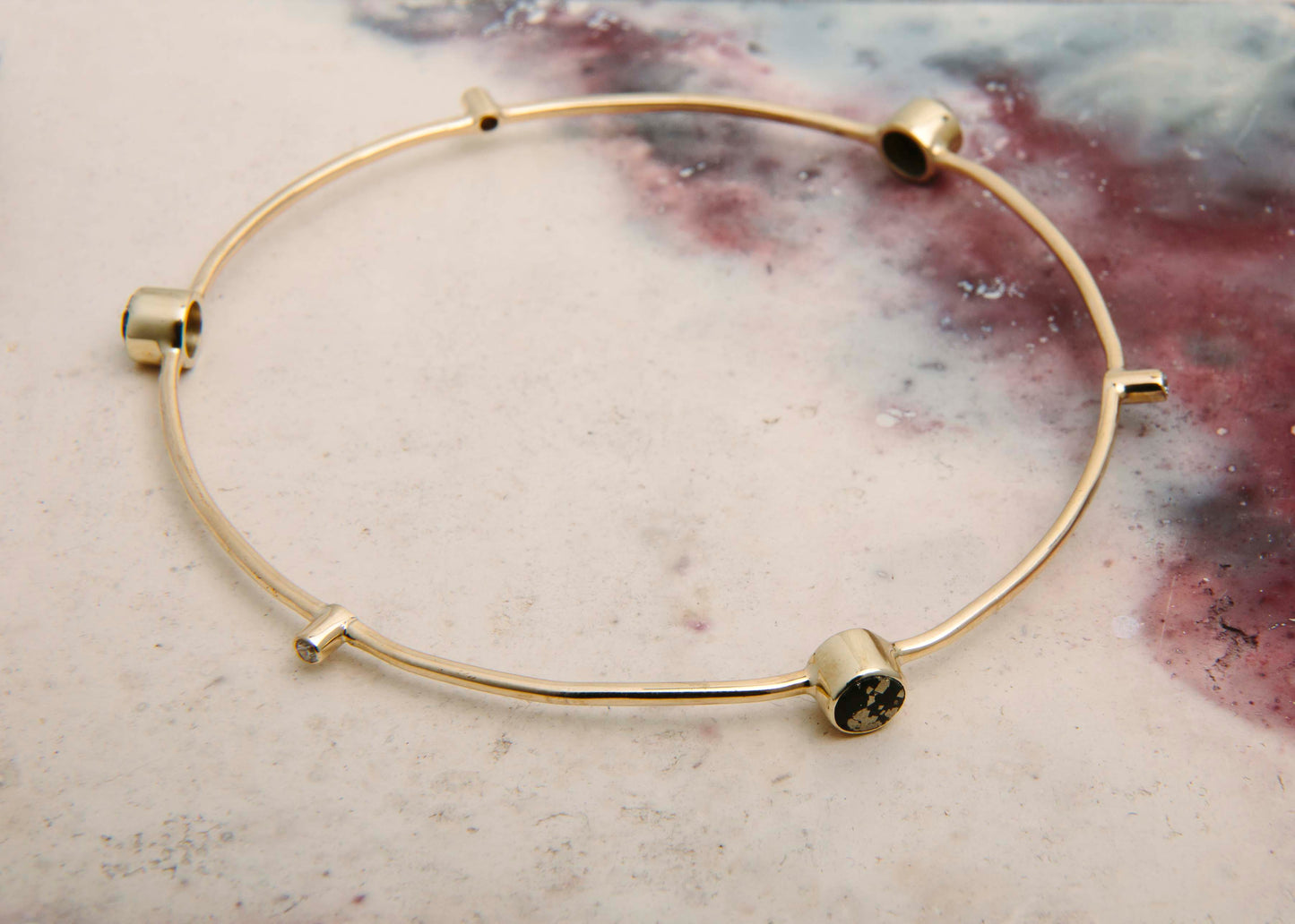 recycled gold bangle with slate pyrite and diamonds on pink marble