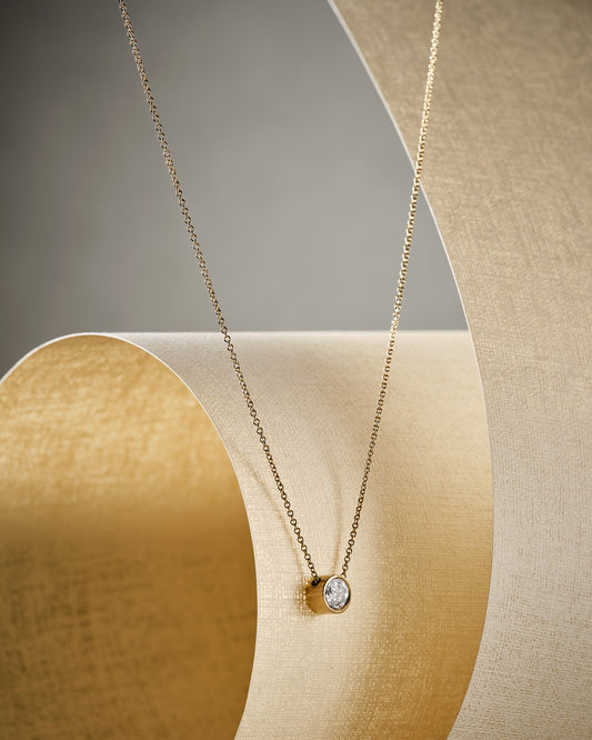 grey salt and pepper diamond necklace on gold chain by beige material