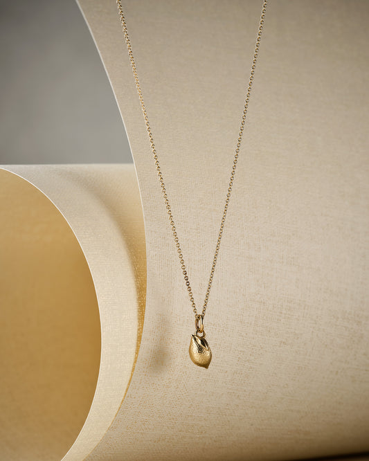 tiny gold lemon necklace on beige background