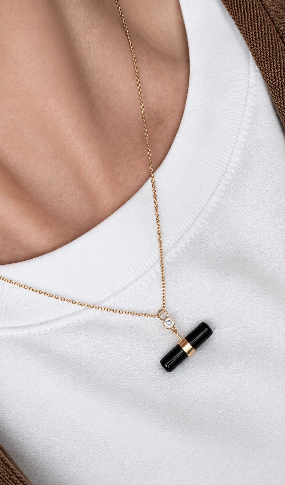 A close-up of a person wearing a delicate black onyx t-bar style necklace. Diamond accent.