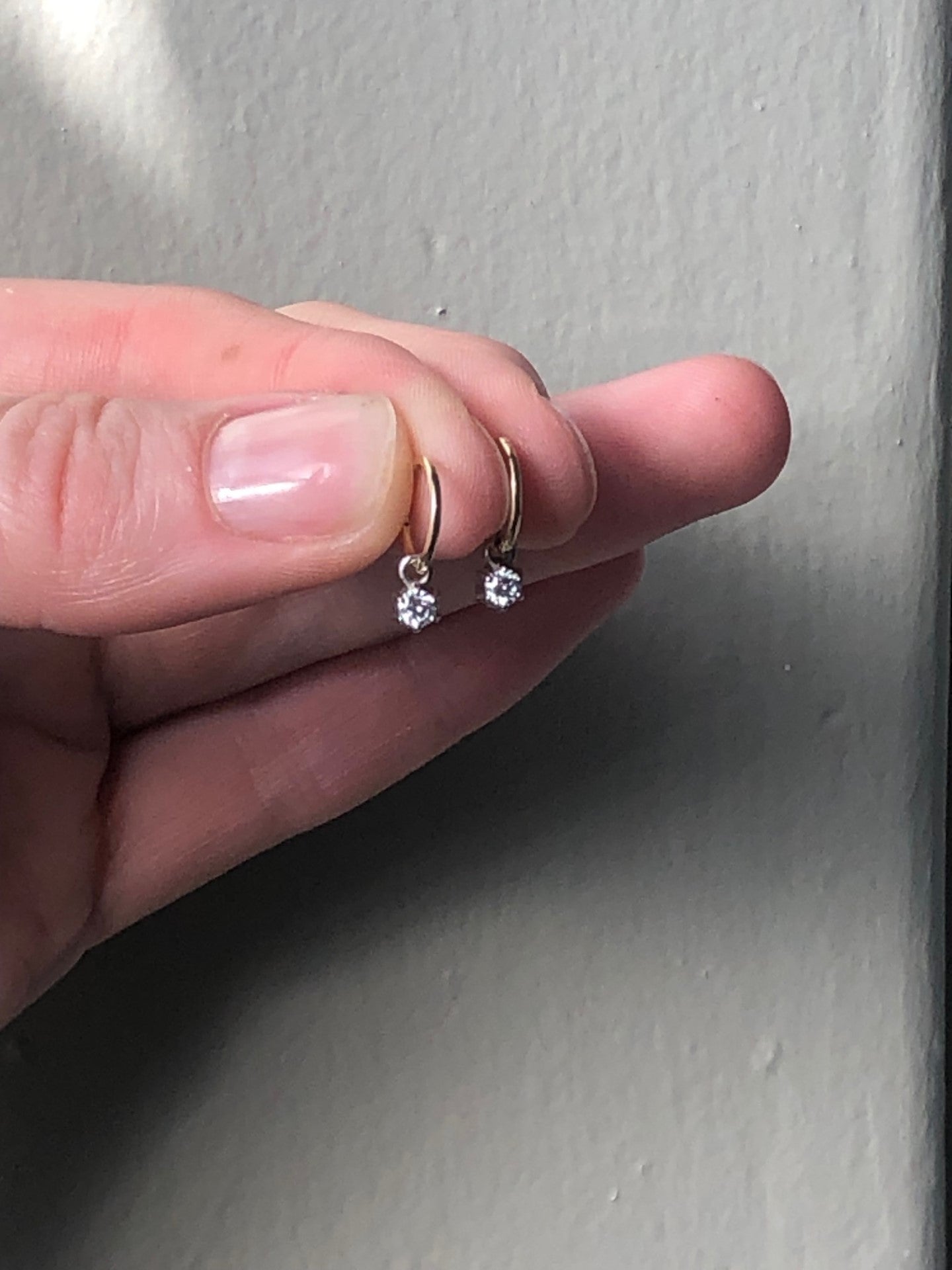 gold hoop diamond star earrings in fingers