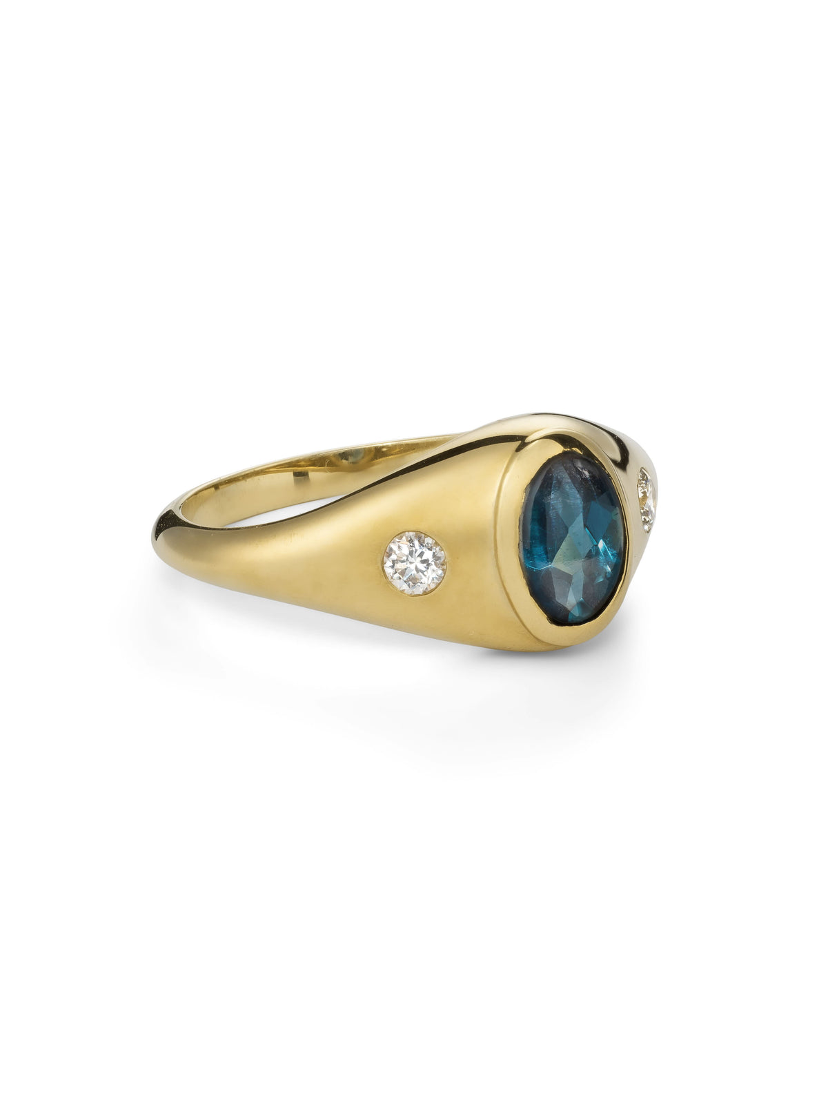 A yellow gold signet ring featuring a an oval-cut London blue topaz and two white diamonds photographed from the side.