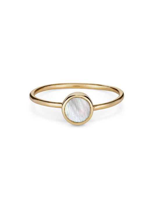 A delicate yellow gold stacking ring featuring a disc of white mother of pearl in a rubover setting on a round wire band.