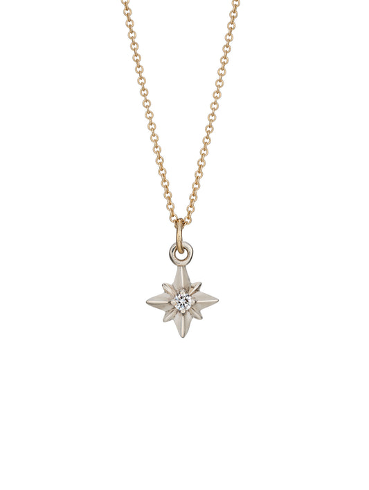 A silver pointed star necklace pendant with a central diamond, attached to a yellow gold chain.