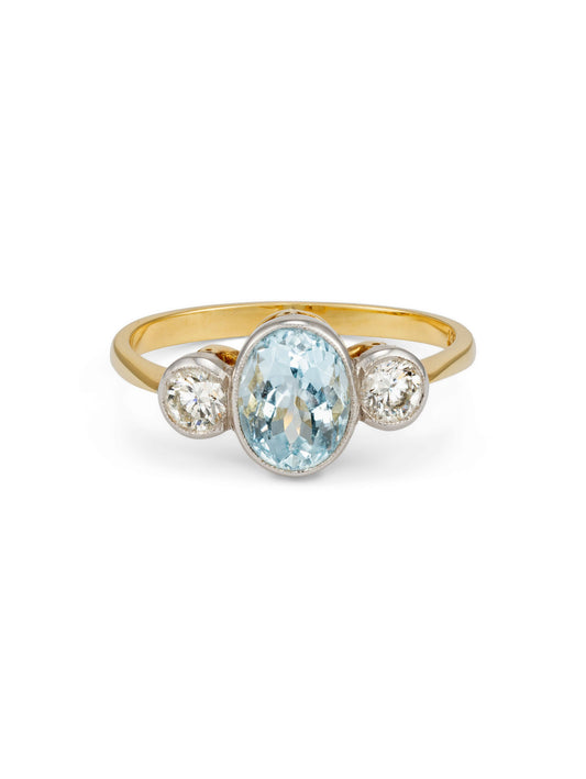 A vintage yellow gold ring featuring an oval-cut Aquamarine center stone and two round-cut diamonds.