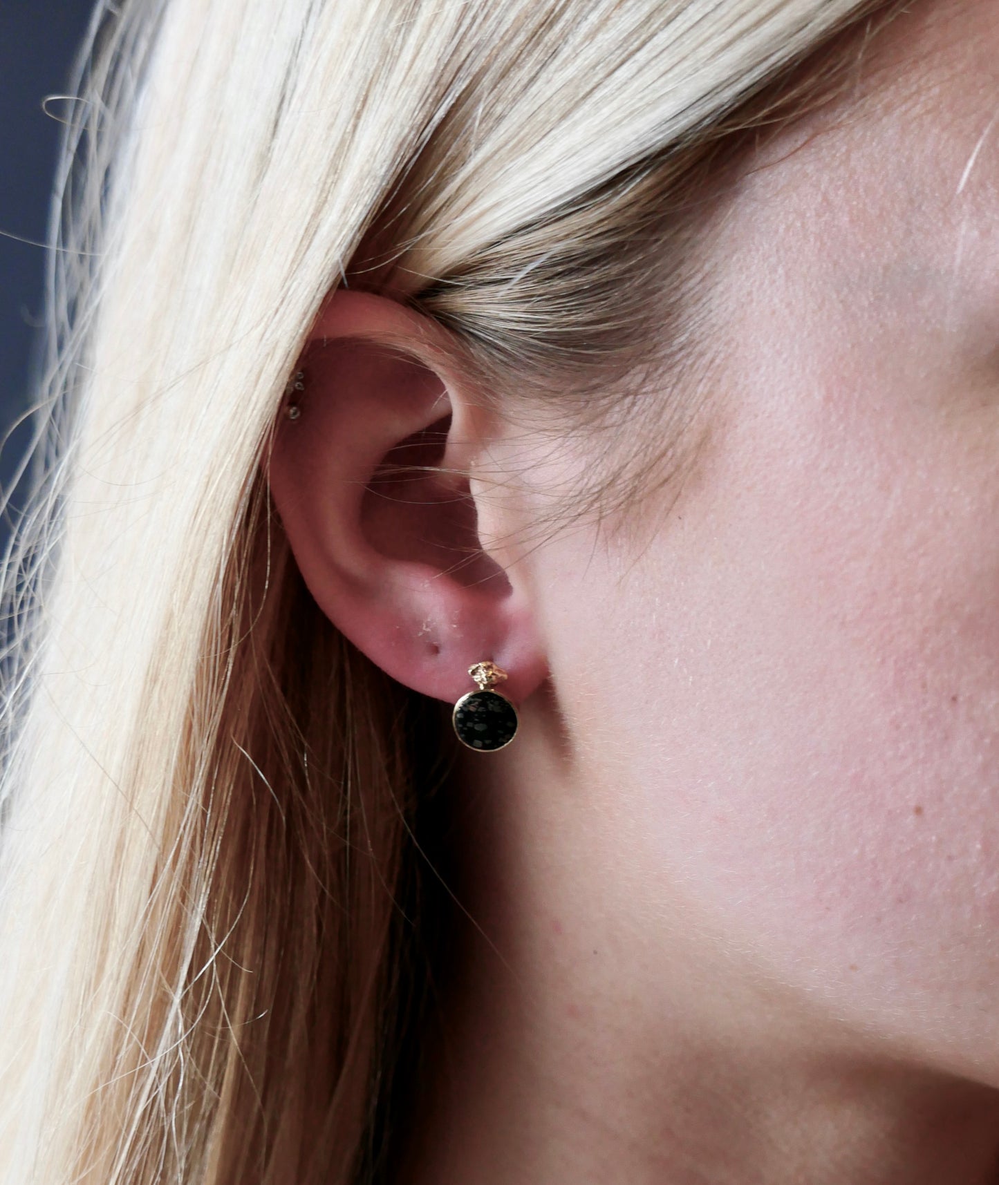black and gold earring studs on model