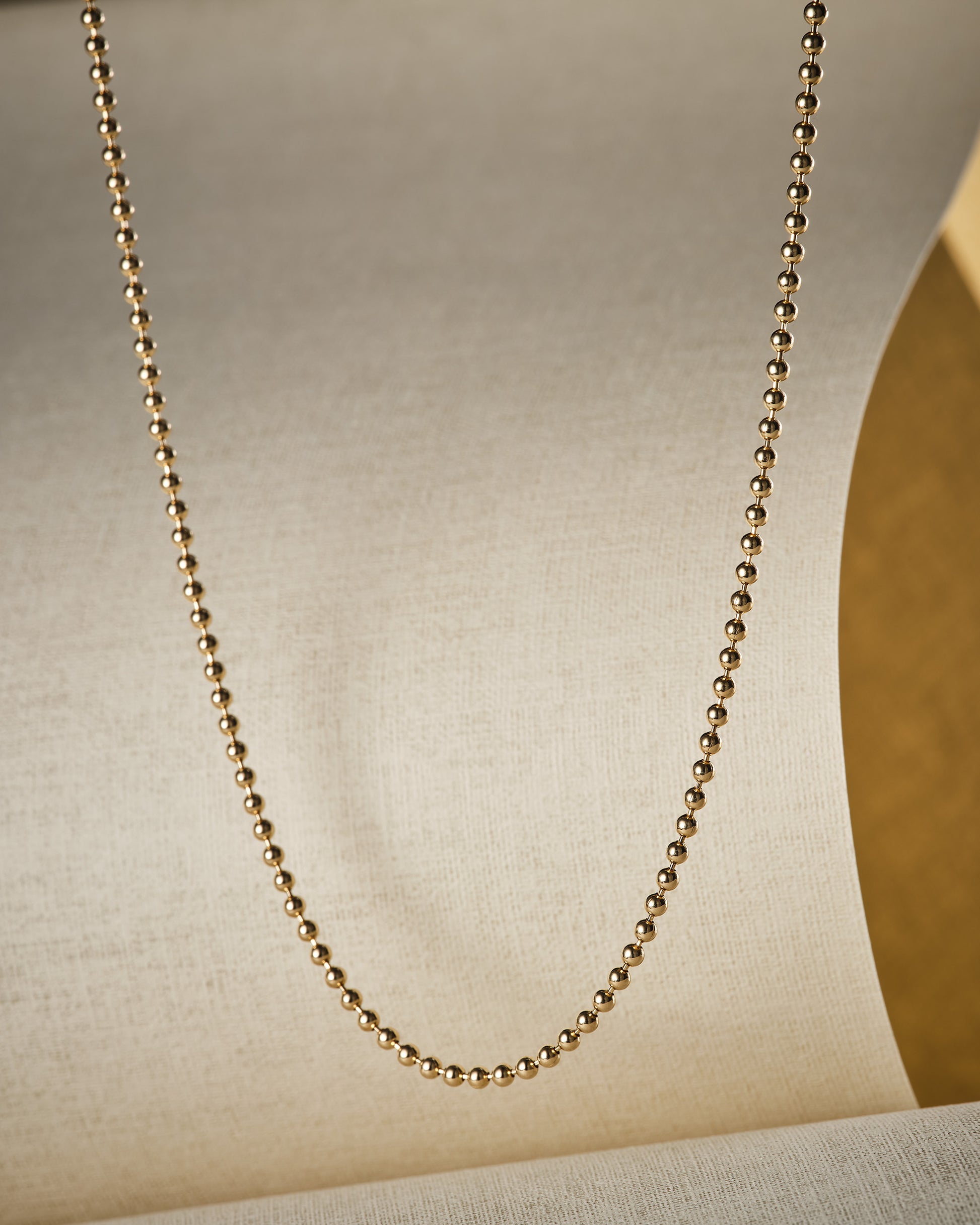 solid gold ball chain on beige background