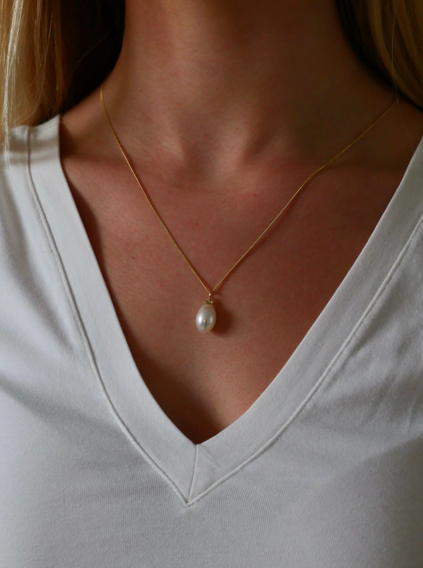 Baroque pearl and gold nugget pendant necklace on model with white v-neck tshirt