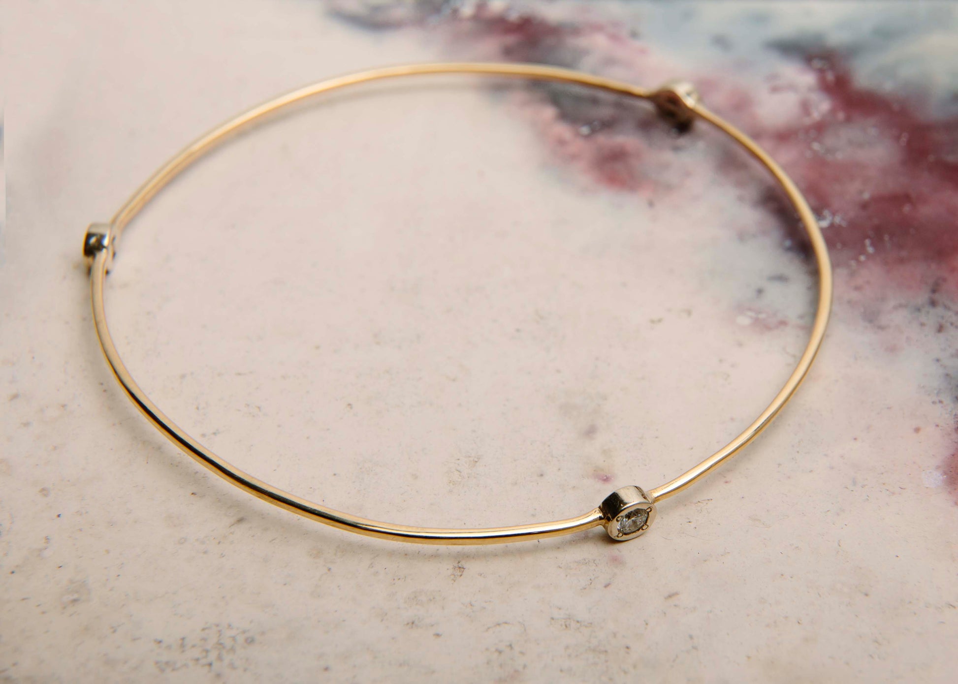 handmade solid gold bangle with diamond studs on pink marbled table