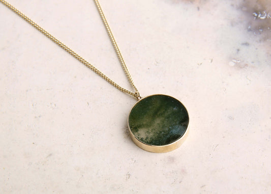 handmade moss agate green disc and gold pendant necklace on pink marble