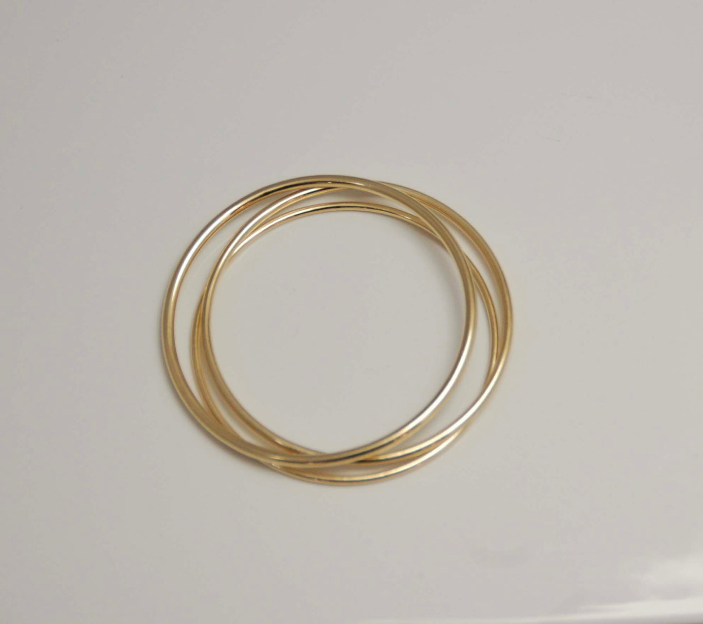 3 handmade solid gold bangles on white table