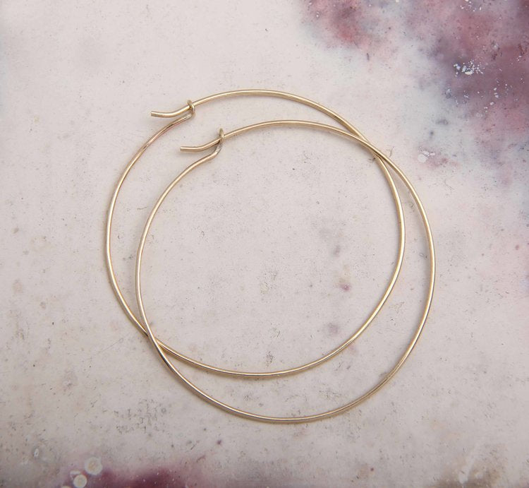 large solid gold hoop earrings on pink marble