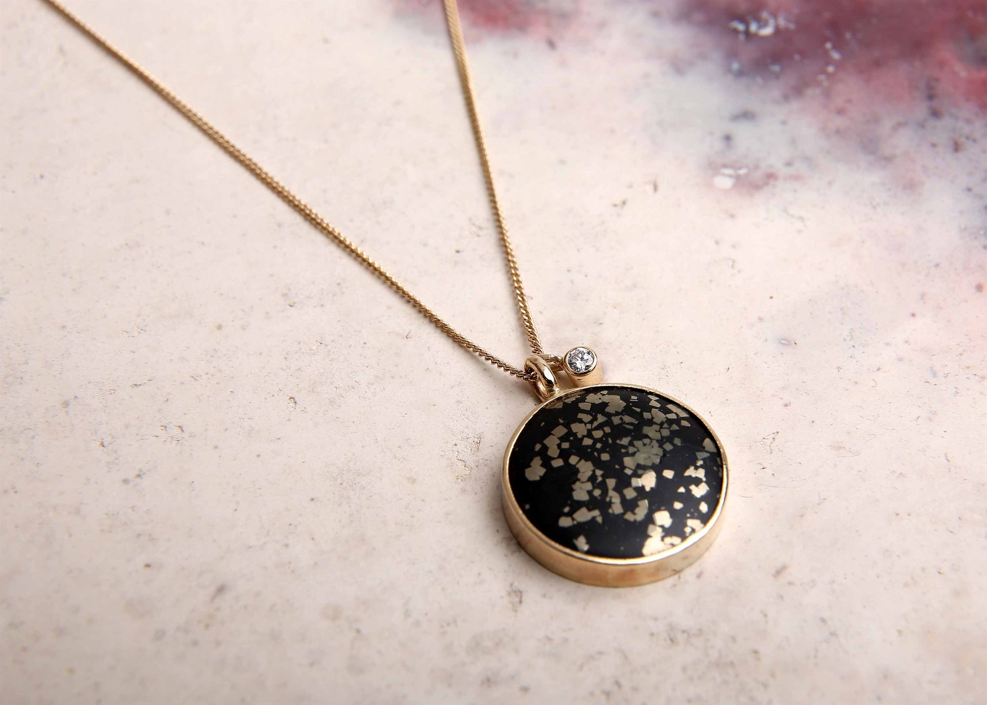 black and gold slate pyrite pendant gold necklace with diamond on pink marbled background