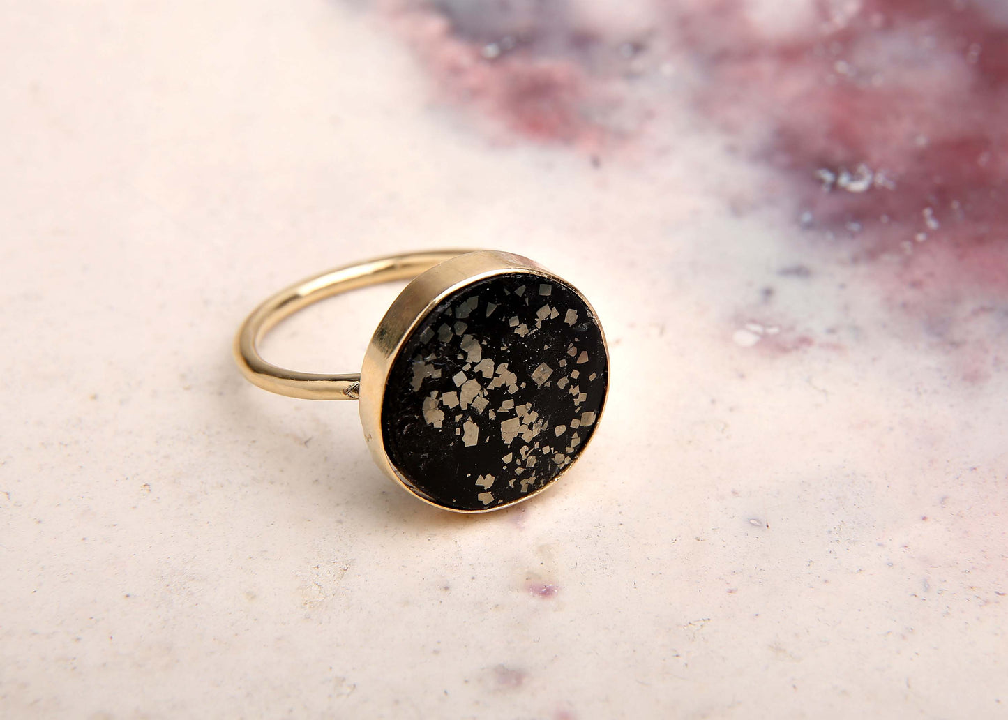 large black and gold stellar cocktail ring on pink marbled background