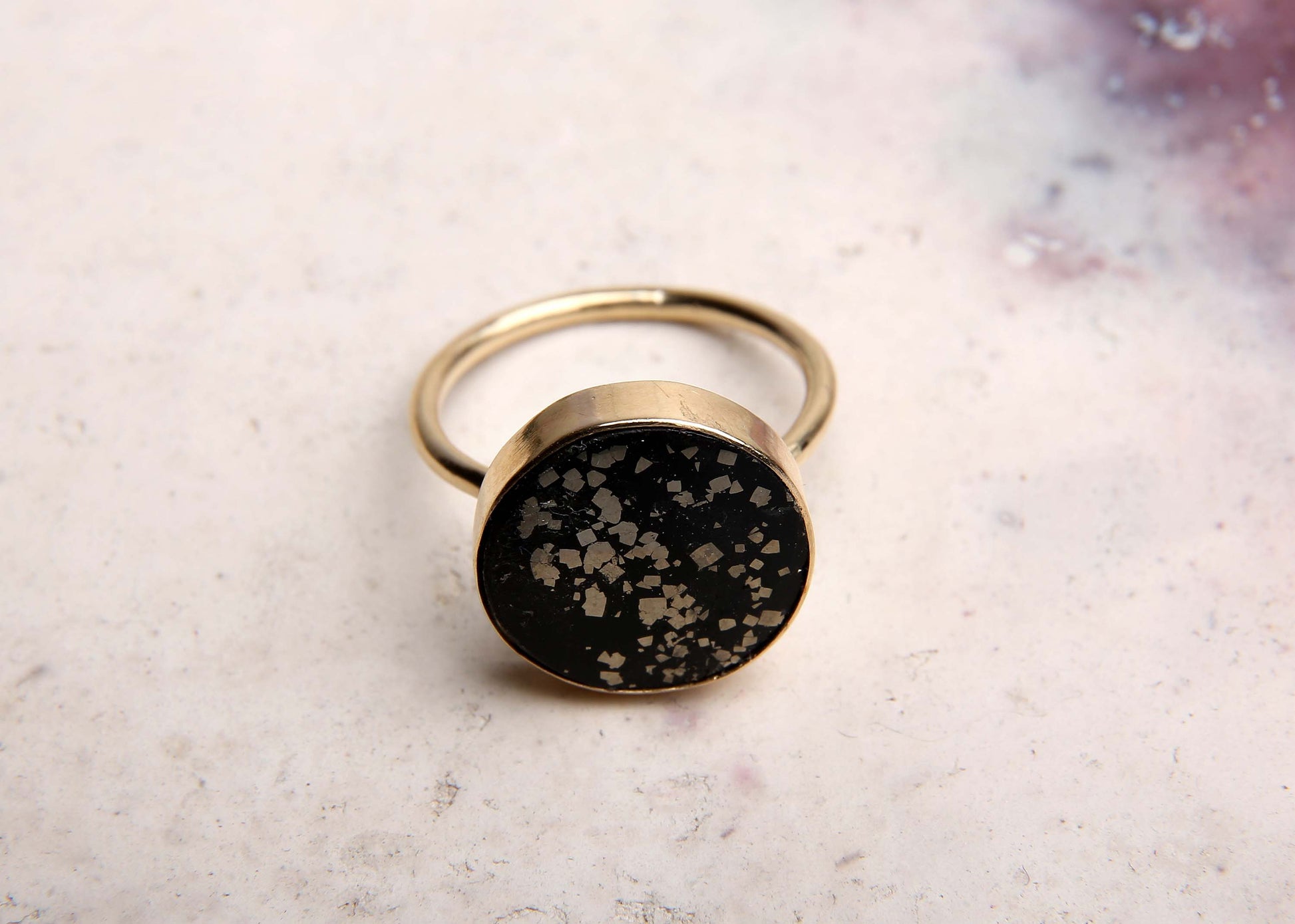 large black and gold stellar cocktail ring on pink marbled background front view