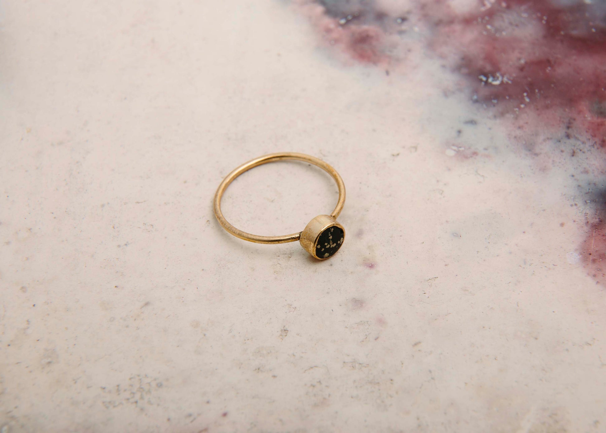 stellar black and gold ring on pink marble background