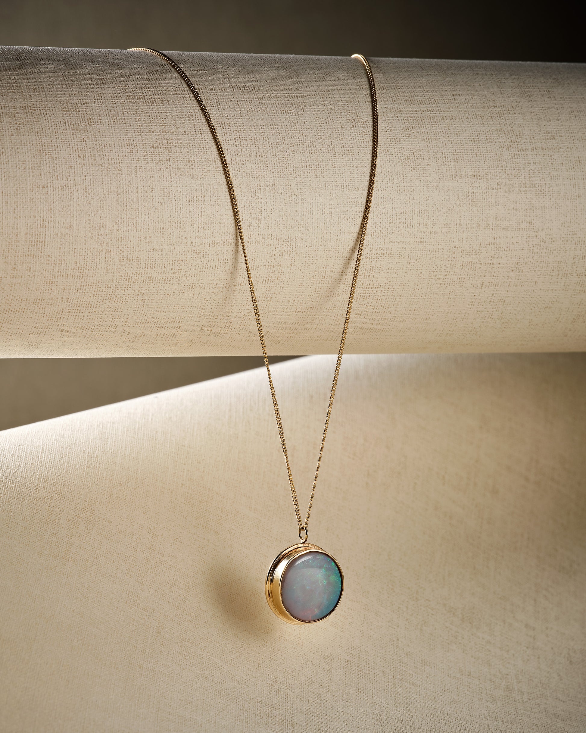 white opal and solid gold pendant necklace on beige background