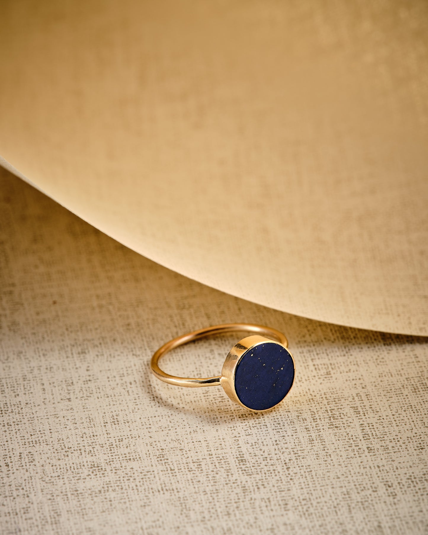 Stellar blue lapis lazuli gold disc ring with beige background