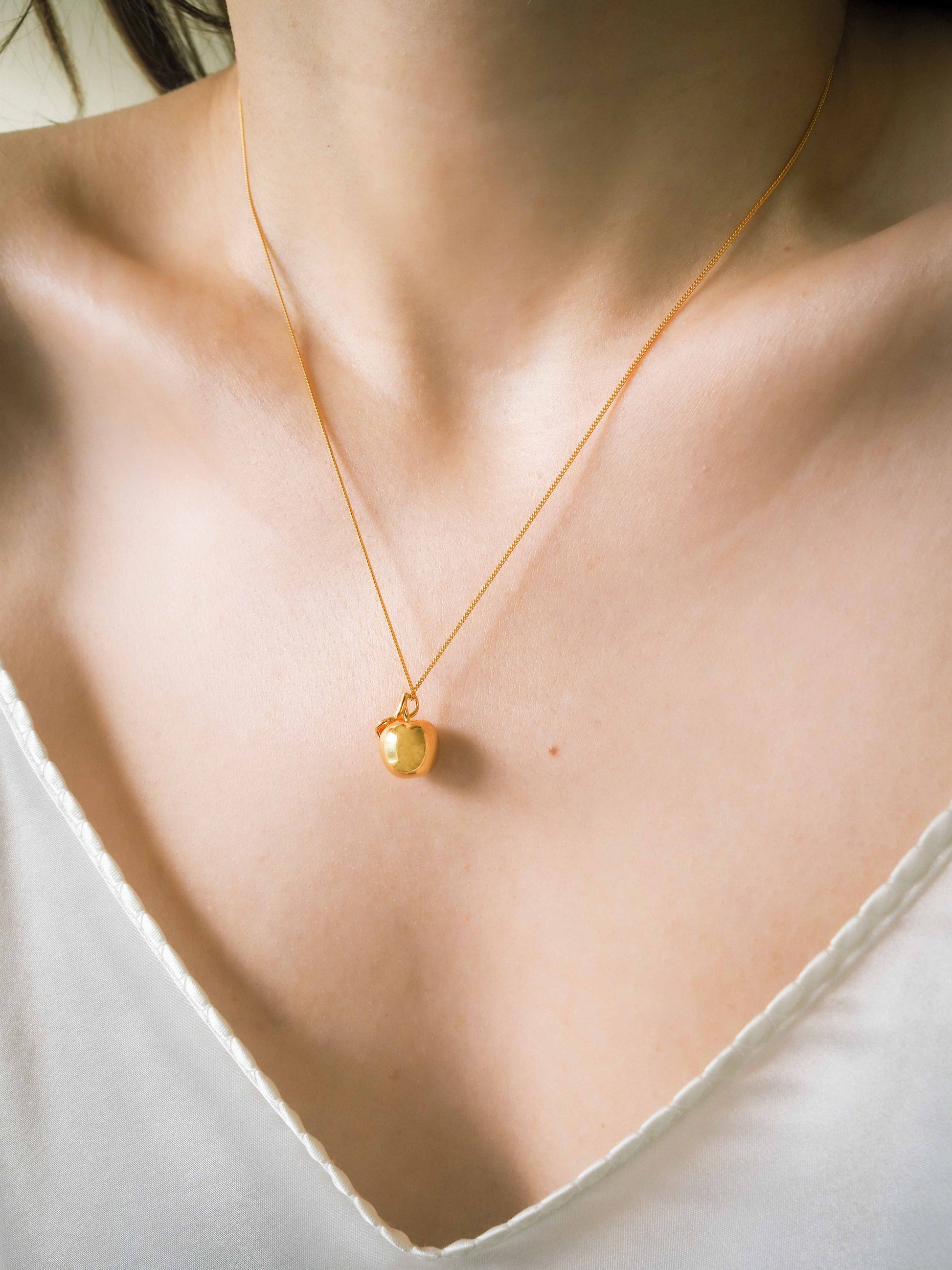 gold apple necklace on model 